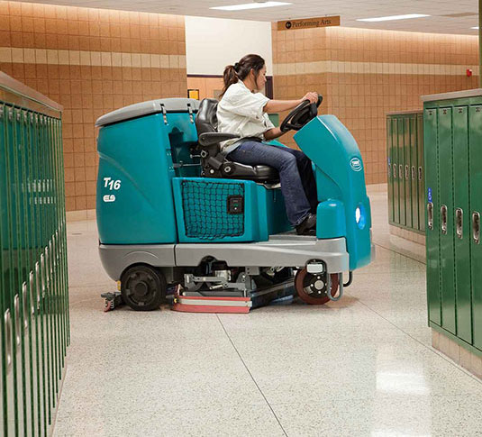 A T16 Battery-Powered Rider Scrubber cleaning a school floor.