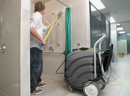 An employee cleaning a shower with the ASC-15 All-Surface Cleaner
