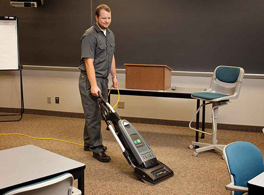 V-DMU-14 Dual Motor Upright Vacuum vacuuming a classroom floor.