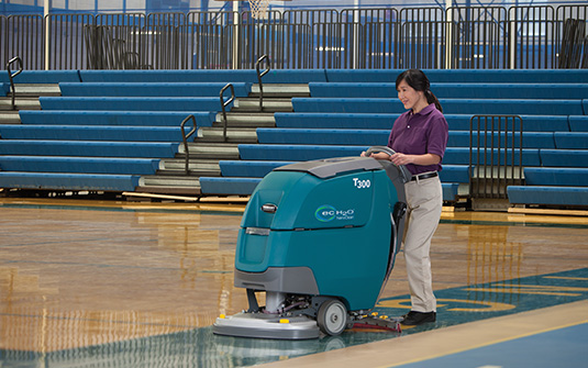 Tennant t300 floor scrubber cleaning a school gymnasium wooden floor Tennant t300 floor scrubber cleaning a school gymnasium wooden floor