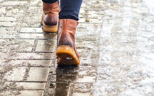 a person wearing snow boots walking on an icy footpath a person wearing snow boots walking on an icy footpath