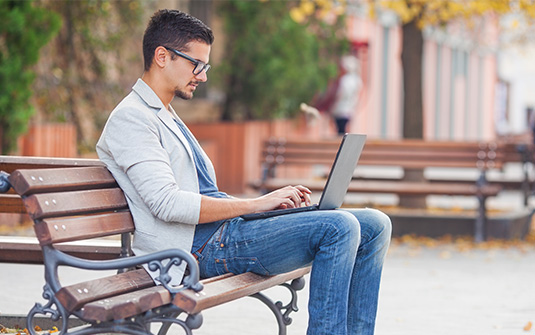 remote worker on laptop outside on bench remote worker on laptop outside on bench