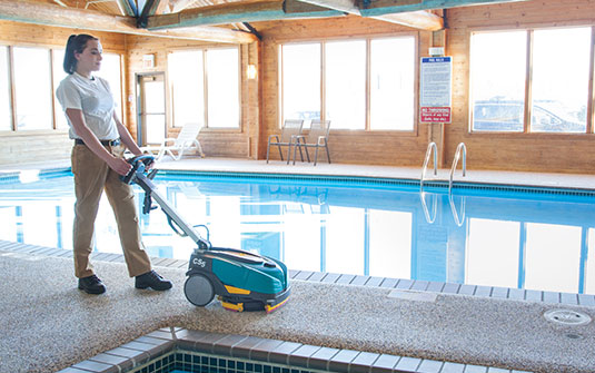 Tennant CS5 walk behind floor scrubber cleaning a residential pool area Tennant CS5 walk behind floor scrubber cleaning a residential pool area