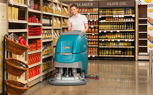 A worker maintains a polished concrete floor with an auto scrubber. A worker maintains a polished concrete floor with an auto scrubber.