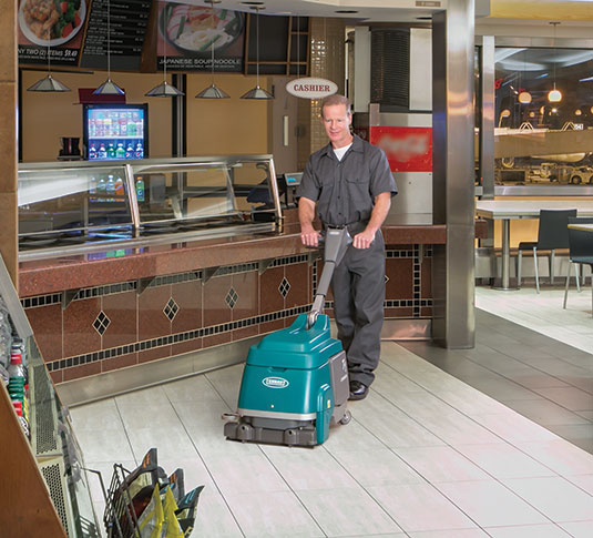 A worker cleans a small format restaurant with a small battery auto scrubber A worker cleans a small format restaurant with a small battery auto scrubber