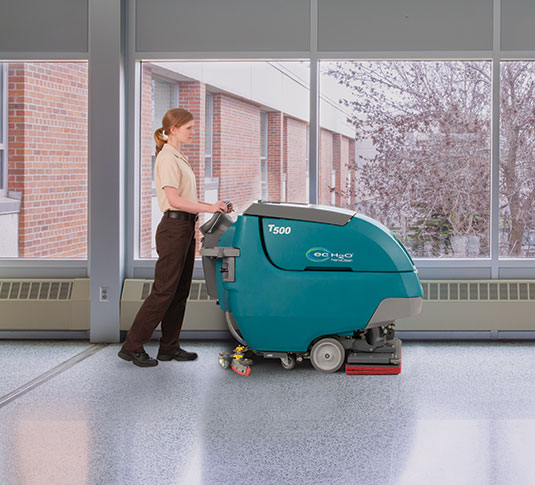 Facility Manager cleaning floor with orbital floor scrubber