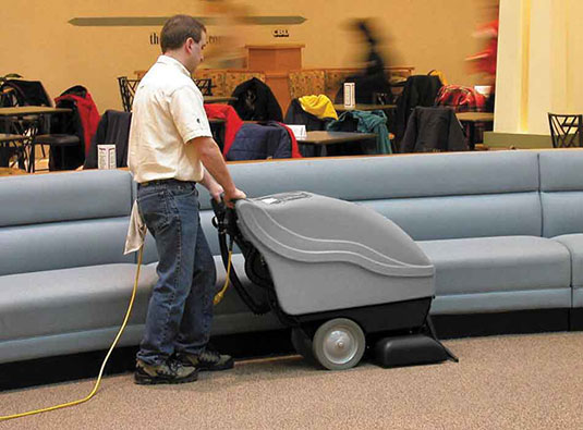 cleaning staff using a Tennant Company walk-behind carpet extractor to clean carpet in school auditorium cleaning staff using a Tennant Company walk-behind carpet extractor to clean carpet in school auditorium