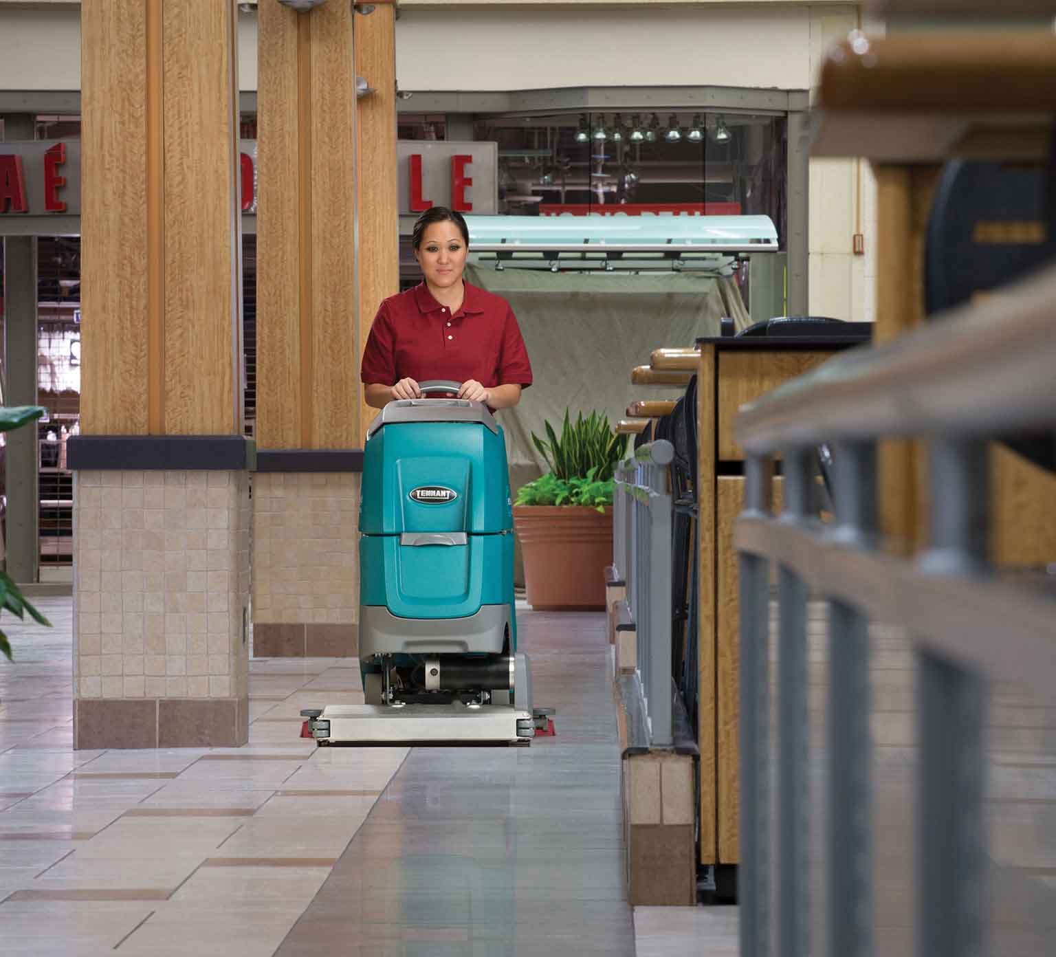 un limpiador que utiliza la restregadora de pisos de operador caminando para limpiar un centro comercial un limpiador que utiliza la restregadora de pisos de operador caminando para limpiar un centro comercial